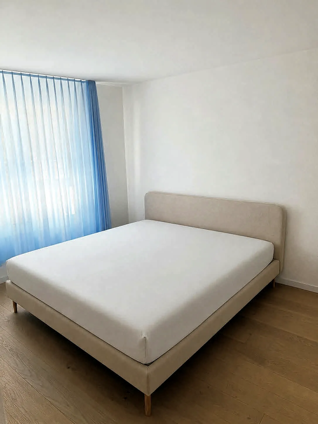 Helles Schlafzimmer mit Parkettboden und Vorhängen